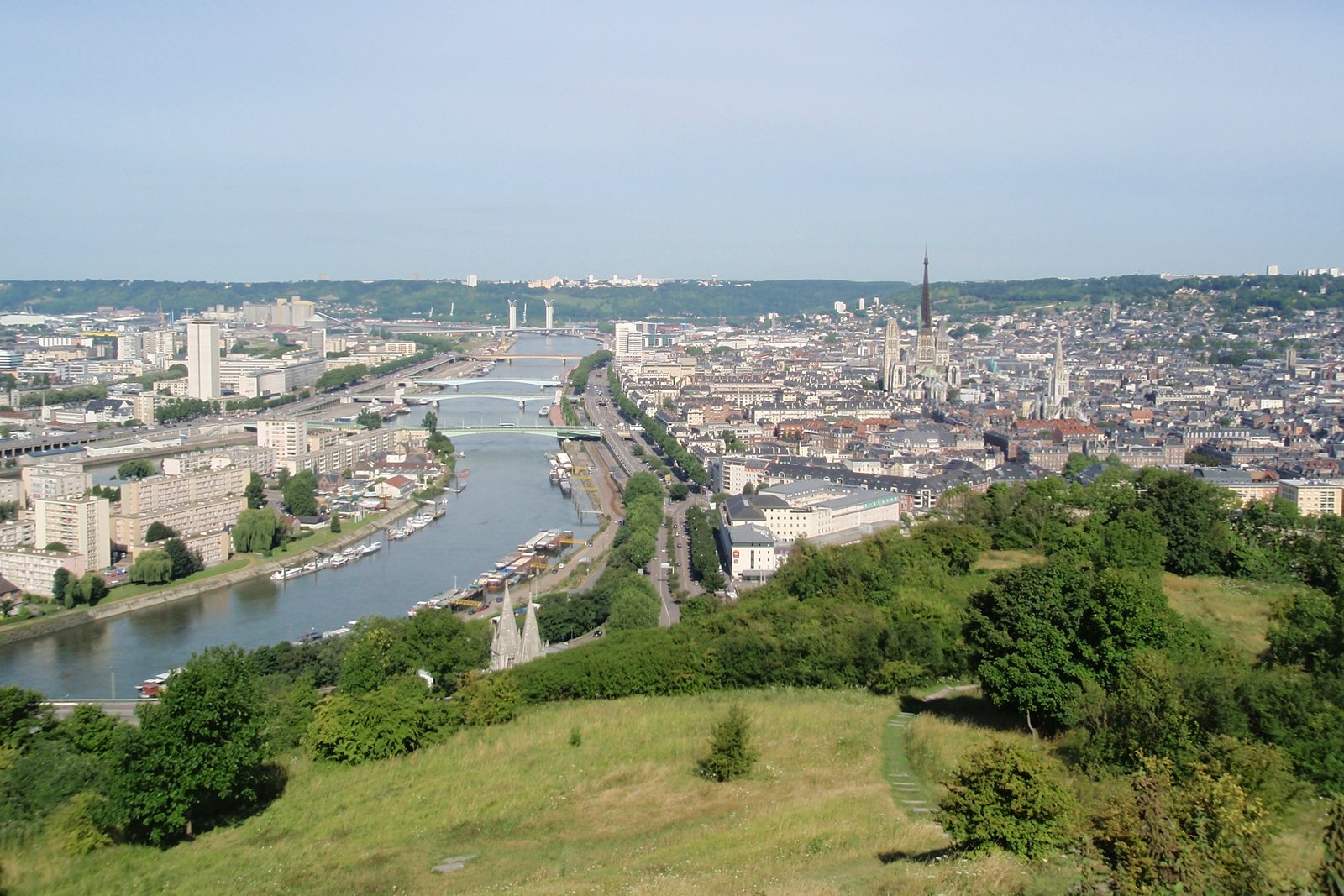 Vue panoramique de Rouen depuis la côte Sainte-Catherine : la Seine et ses ponts à gauche, la flèche de la cathédrale Notre-Dame au-dessus des toits du centre-ville
